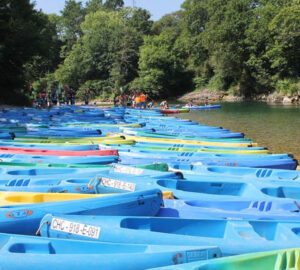 Multitud de canoas en las orillas del río Sella con gente disfrutando del descenso en canoa. cuánto cuesta hacer el Descenso del Sella 2022