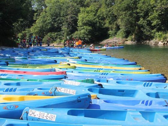 Multitud de canoas en las orillas del río Sella con gente disfrutando del descenso en canoa. cuánto cuesta hacer el Descenso del Sella 2022