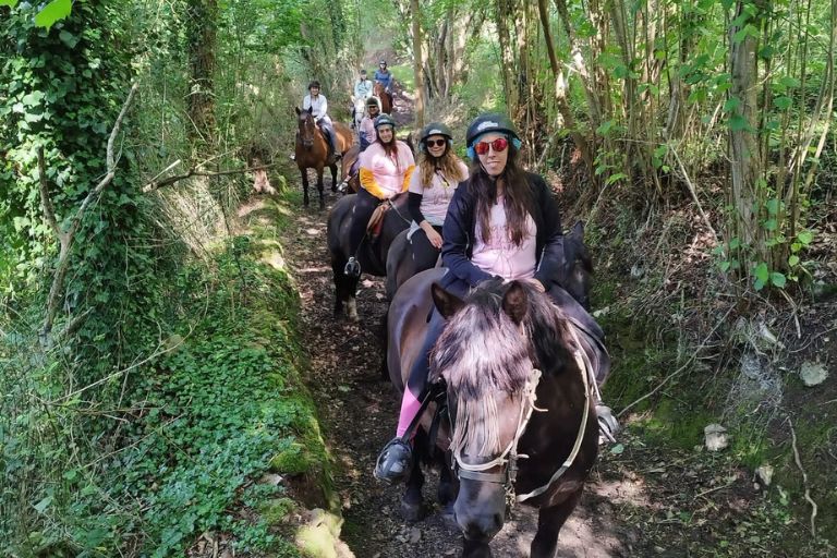 Grupo de personas montadas a caballo haciendo una ruta con niños - Los Cauces