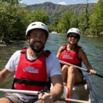 Dos personas disfrutando del Descenso del Sella en kayak con chalecos rojos de Los Cauces y paisaje natural de Asturias.
