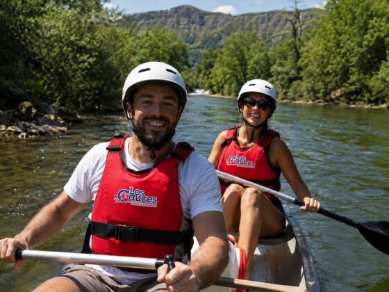 Dos personas disfrutando del Descenso del Sella en kayak con chalecos rojos de Los Cauces y paisaje natural de Asturias.