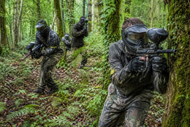 Jugadores de paintball avanzando entre árboles y helechos en un bosque asturiano.