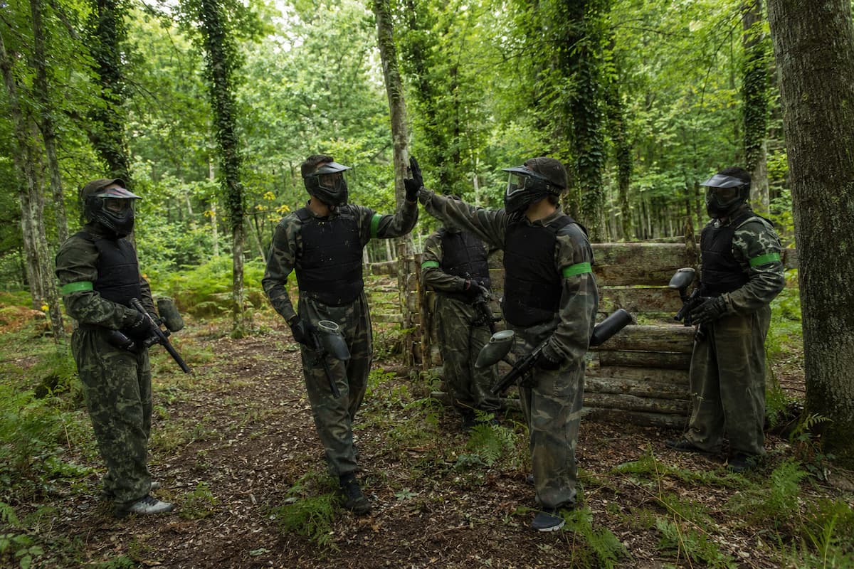 Equipo de paintball celebrando la partida en una zona de juego dentro de un bosque asturiano.