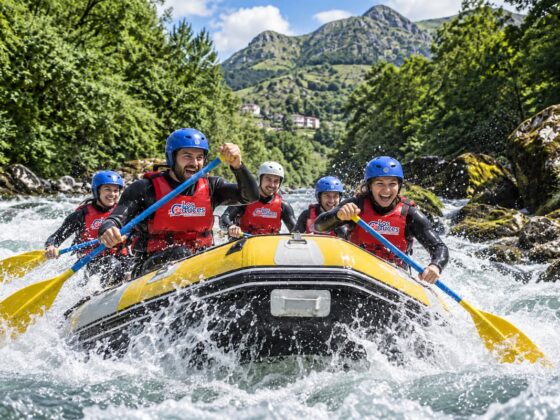 Grupo practicando rafting en Asturias con chalecos rojos de Los Cauces en un río de aguas bravas.